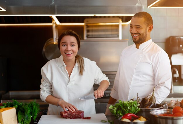 Guapo joven chef africano está cocinando junto con su novia en la cocina