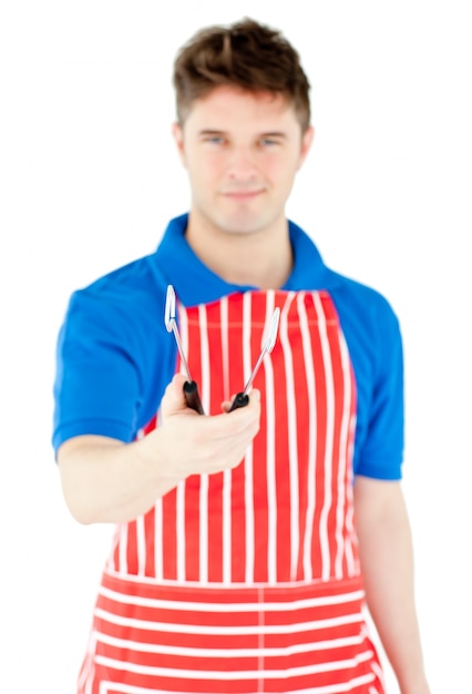 Guapo joven cocinero sosteniendo un utensilio de cocina