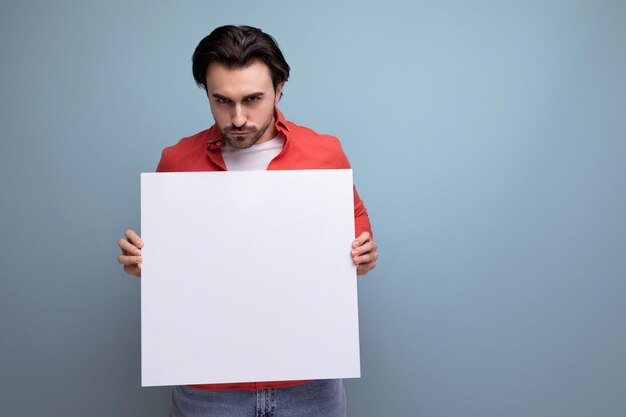 Foto guapo joven moreno bien arreglado mostrando publicidad en pantalla en blanco