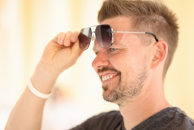 Guapo levanta gafas con la mano hacia arriba de los ojos.