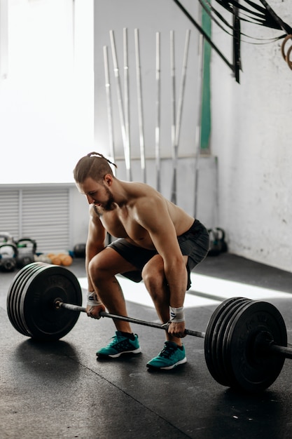 Guapo levantador de pesas preparándose para el entrenamiento con barra