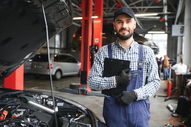 El guapo mecánico de automóviles está posando en un servicio de automóviles