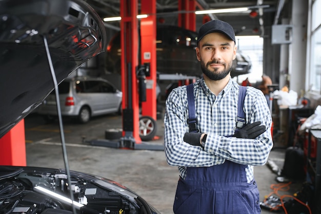 El guapo mecánico de automóviles está posando en un servicio de automóviles