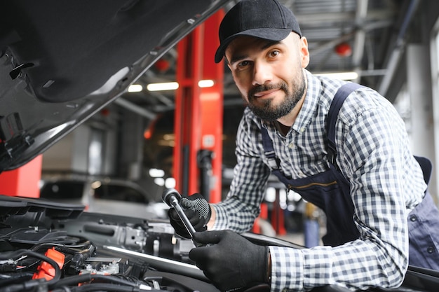 El guapo mecánico de automóviles está posando en un servicio de automóviles