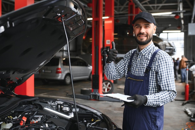 El guapo mecánico de automóviles está posando en un servicio de automóviles