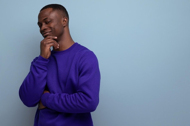 Guapo moreno bien arreglado joven americano en sudadera azul en el fondo con espacio de copia