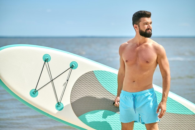 Un guapo moreno con un kayak en la playa.