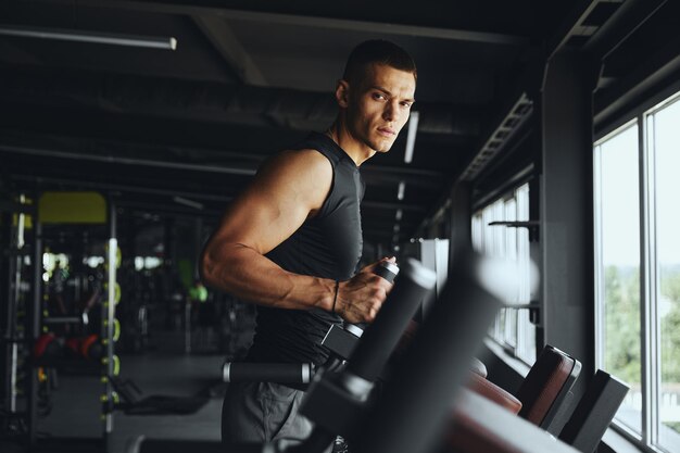 El guapo y musculoso culturista está listo en las barras paralelas preparándose para un intenso y