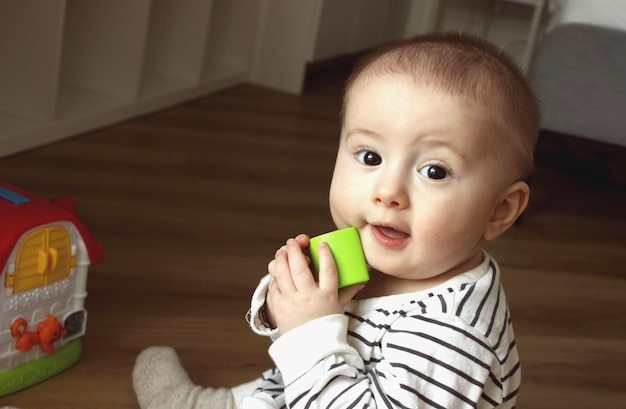 Foto un guapo niño pequeño está jugando con juguetes en la habitación