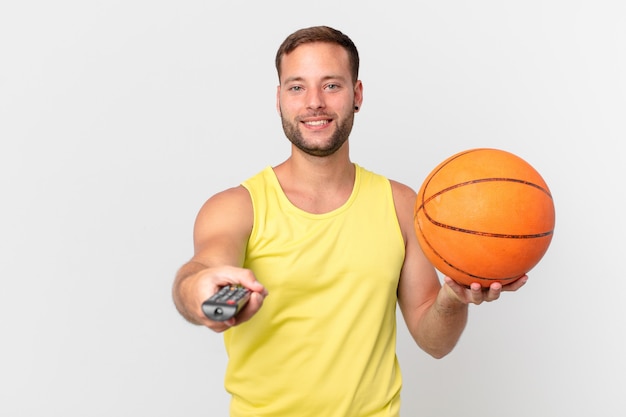 guapo con una pelota de baloncesto y elegir un canal con un controlador