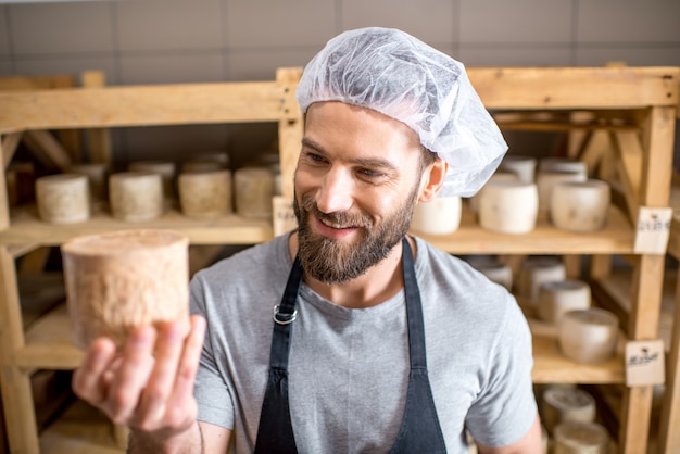 Guapo quesero comprobando el proceso de envejecimiento del queso de cabra de pie en la pequeña bodega