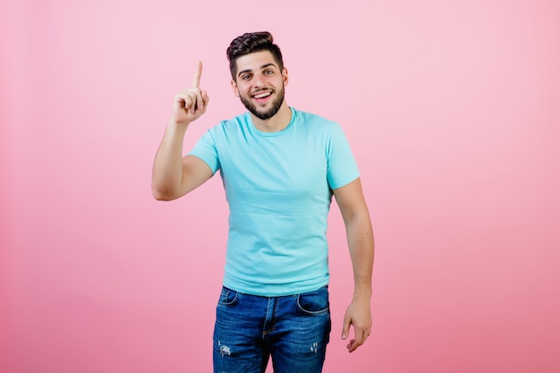 Guapo sonriente joven apuntando el dedo hacia arriba