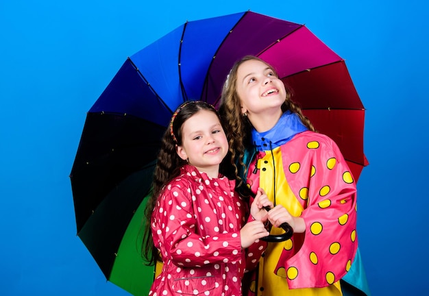 Guarda-chuva brilhante é mais fácil ser feliz juntos seja arco-íris na nuvem de alguém diversão em dia chuvoso passeio feliz sob o guarda-chuva crianças meninas amigos felizes sob o guarda-chuva tempo chuvoso com roupas adequadas