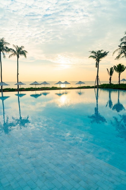 guarda-chuva com piscina ao redor da piscina com fundo do mar oceano ao pôr do sol ou nascer do sol - conceito de férias e férias