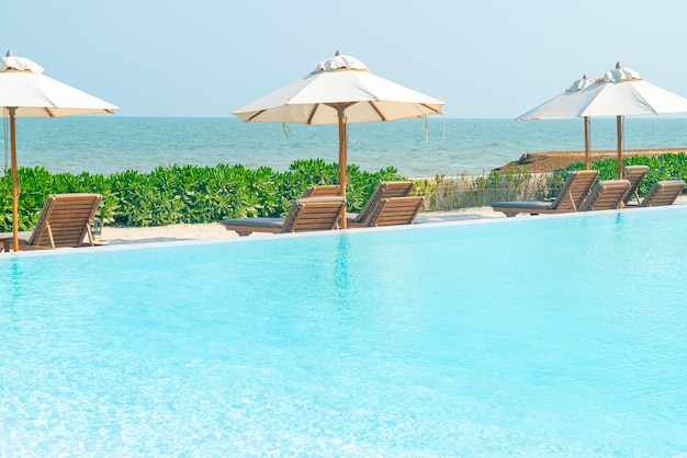 guarda-chuva com piscina ao redor da piscina com fundo do mar oceano - conceito de férias e férias