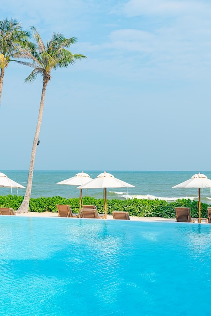 guarda-chuva com piscina ao redor da piscina com fundo do mar oceano - conceito de férias e férias