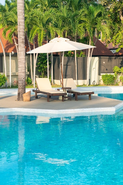 Guarda-chuva com piscina de cama ao redor da piscina com fundo do mar oceano - conceito de férias e férias