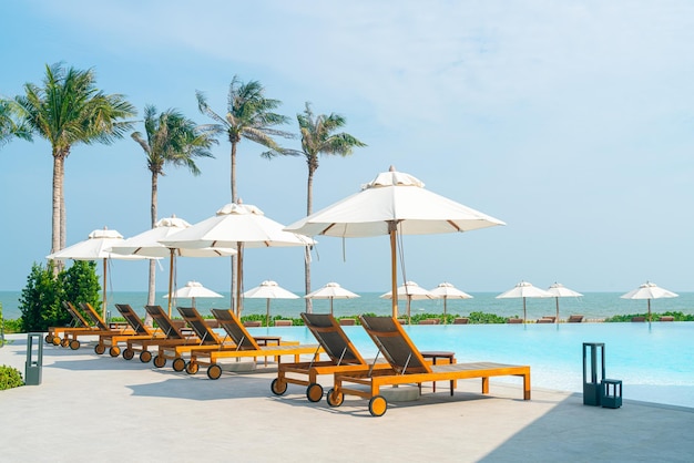 guarda-chuva com piscina de cama ao redor da piscina com fundo do mar oceano - conceito de férias e férias