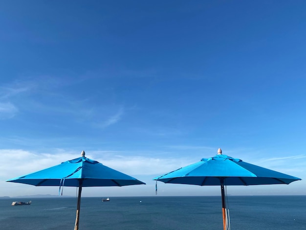 Guarda-chuva de praia azul no fundo do céu azul de verão