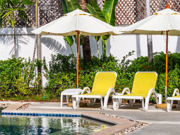 Guarda-chuva e cadeira em torno da piscina exterior de luxo