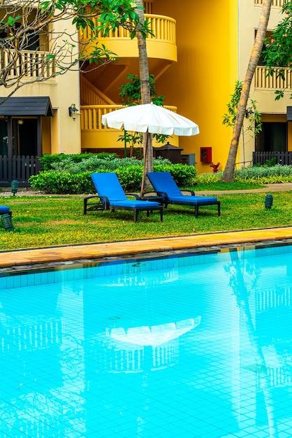 guarda-chuva e cadeira na piscina com árvores