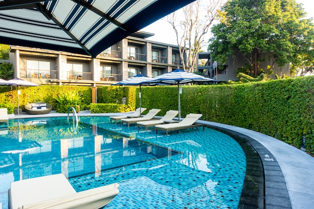 Guarda-chuva e cama de piscina em volta da piscina no hotel resort para viagens de férias