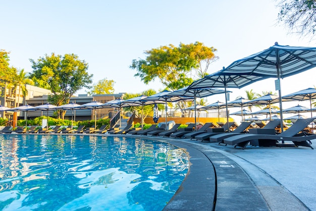 Guarda-chuva e cama de piscina em volta da piscina no hotel resort para viagens de férias