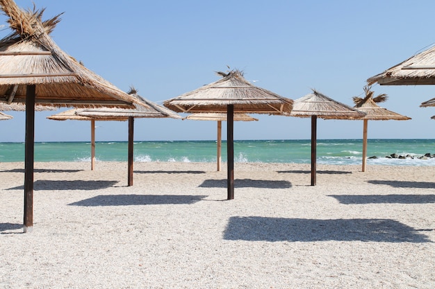 Guarda-chuvas de palha na praia vazia em dia de verão