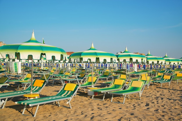 Guarda-chuvas verdes e espreguiçadeiras na praia de Rimini na Itália