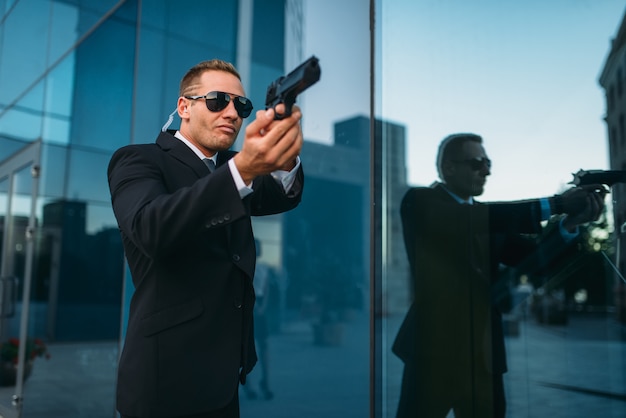 Foto guarda-costas com fone de ouvido de segurança e arma nas mãos