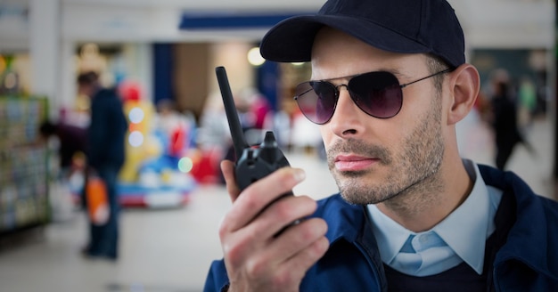 Guarda de segurança com walkie talkie contra centro comercial embaçado