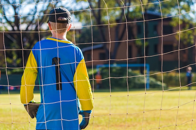 Guarda portero joven portero delante de su objetivo de equipo durante un juego