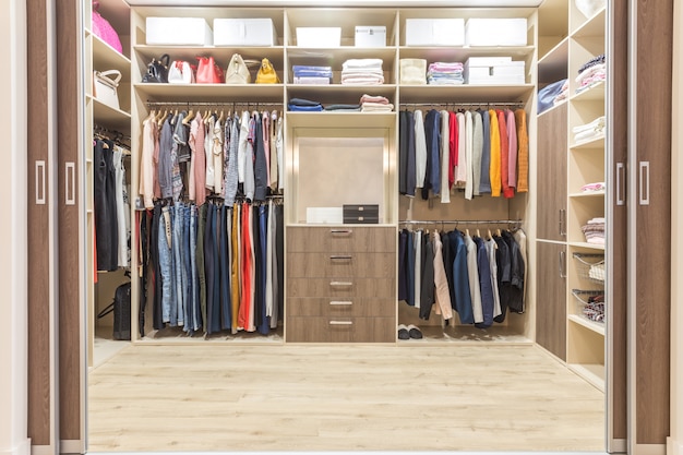Guarda-roupa de madeira moderno com roupas penduradas no trilho em pé no interior do design do armário
