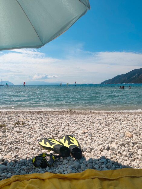 Guarda-sol de férias marítimas nas nadadeiras de mergulho de praia e máscara de mergulho