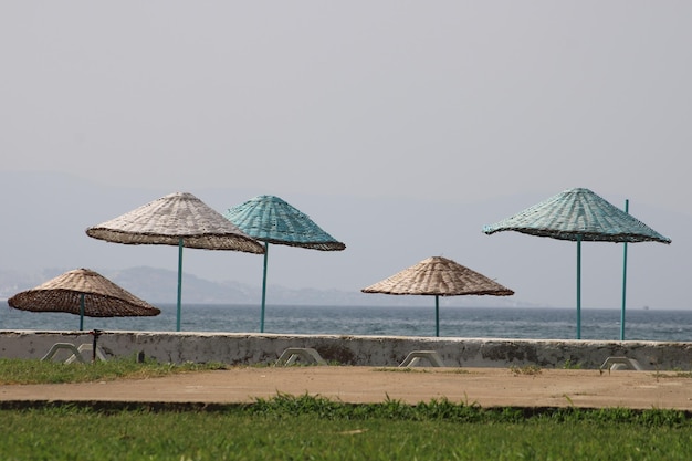 guarda-sol de vime e espreguiçadeira branca de plástico na praia