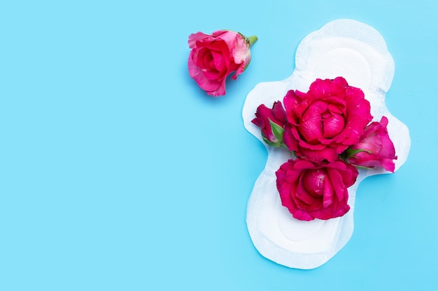 Foto guardanapo higiênico branco com rosas vermelhas na superfície azul