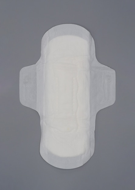 Guardanapo sanitário. almofada de absorvente higiênica macia e confortável e fundo cinza. lençol superior branco. tiro do estúdio isolado. almofadas de pano para a menstruação. tipo asa para a noite. absorvente rápido. sensação de algodão macio.