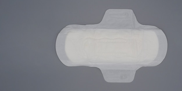 Guardanapo sanitário. almofada de absorvente higiênica macia e confortável e fundo cinza. lençol superior branco. tiro do estúdio isolado. almofadas de pano para a menstruação. tipo asa para a noite. absorvente rápido. sensação de algodão macio.