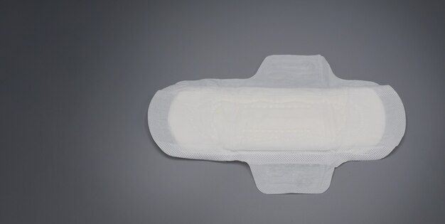 Guardanapo sanitário. Almofada de absorvente higiênica macia e confortável e fundo cinza. Lençol superior branco. Tiro do estúdio isolado. Almofadas de pano para a menstruação. Tipo asa para a noite. Absorvente rápido. sensação de algodão macio.