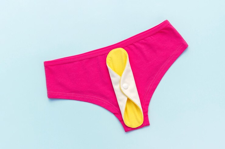 Foto guardanapo sanitário lavável de carvão de bambu amarelo eco almofada menstrual reutilizável e cuecas em fundo azul conceito de saúde das mulheres alternativas ecologicamente corretas de zero desperdício