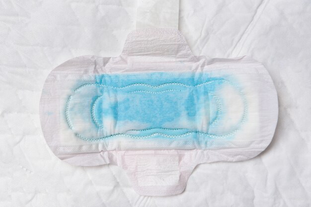 Foto guardanapo sanitário ou absorvente feminino com teste de água azul para absorver a água