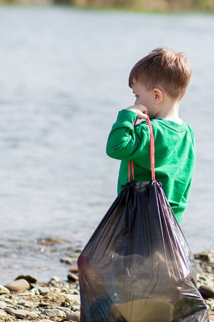 Guardar el concepto de medio ambiente con un niño recogiendo basura