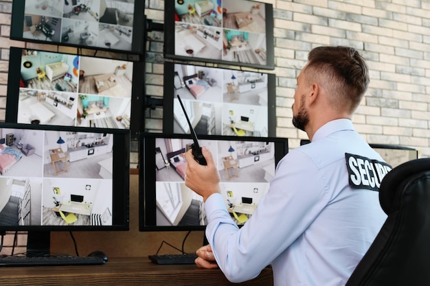 Foto guardia de seguridad masculino con transmisor portátil monitoreando modernas cámaras cctv en interiores