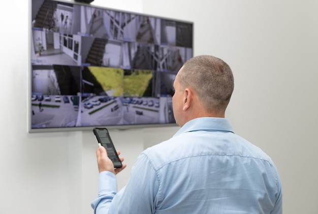 Guardia de seguridad de pie frente a un gran monitor CCTV