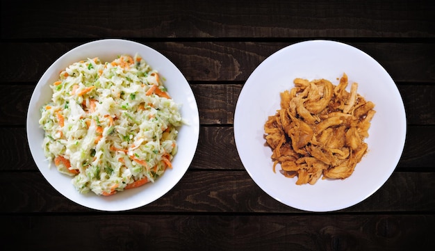 Las guarniciones son un plato de chuleta de pollo dulce y ensalada de col en un plato blanco