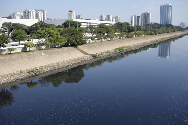 Águas escuras do rio Tietê refletindo o céu e a ponte São Paulo Brasil