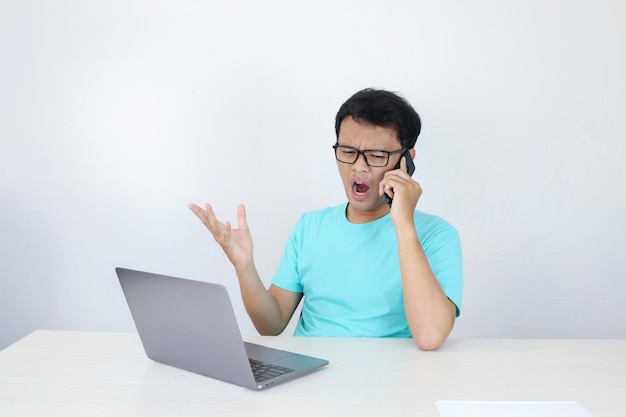 Guau, la cara de un joven asiático se sorprendió por lo que vio en una computadora portátil cuando llamó por teléfono a un hombre indonesio con camisa azul