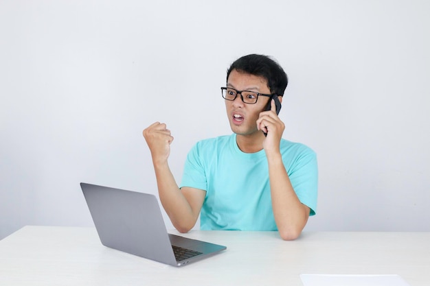 Guau, la cara de un joven asiático se sorprendió por lo que vio en una computadora portátil cuando llamó por teléfono a un hombre indonesio con camisa azul