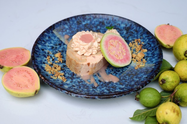 Guava Roll Cake auf blauem Teller auf hellem Hintergrund mit reifen Guavenfrüchten