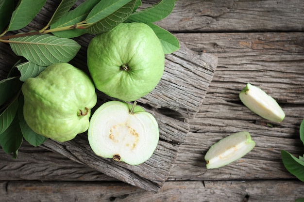 Guayaba fresca con hojas verdes sobre fondo de madera.